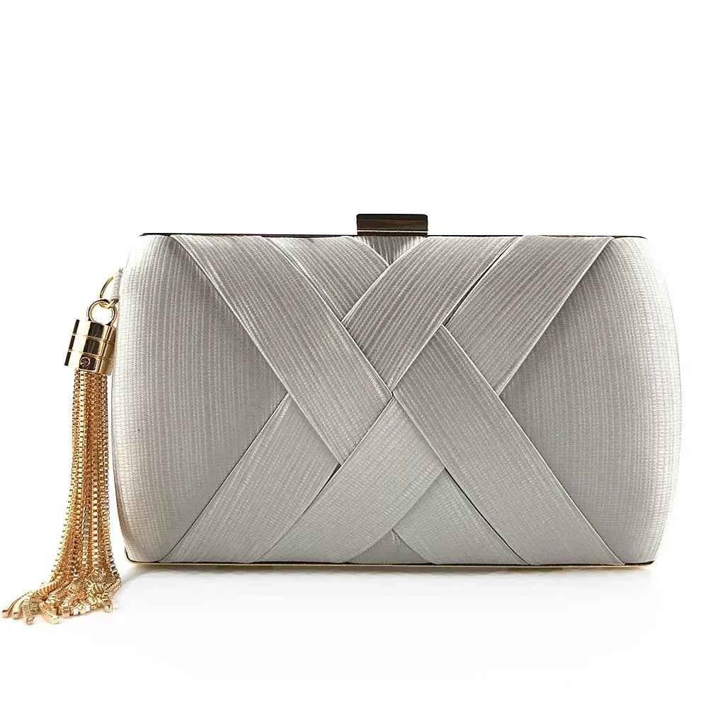 Silver clutch bag with braided design and gold tassel on a white background