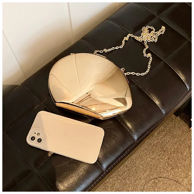 Stylish Acrylic Shell Shape Clutch Bag in Gold with a Chain Strap, alongside a smartphone