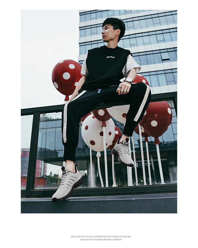 VaultHaus lightweight athletic sneakers for men worn by a man in sporty black and white outfit sitting outdoors