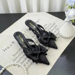 Stylish black pointed toe heels with bow detail, perfect for pairing with chic outfits
