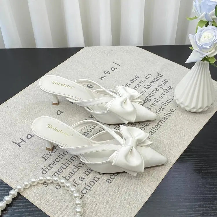 Elegant white slingback heels with bow detail, perfect for pairing with French style pink slippers