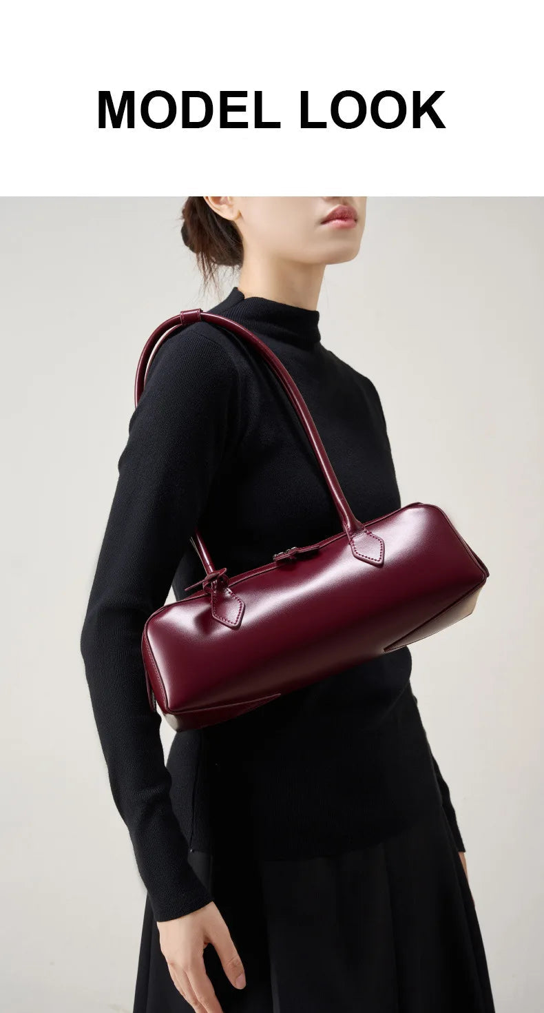 Stylish ladies baguette shoulder bag in burgundy, worn elegantly by a model in a black outfit