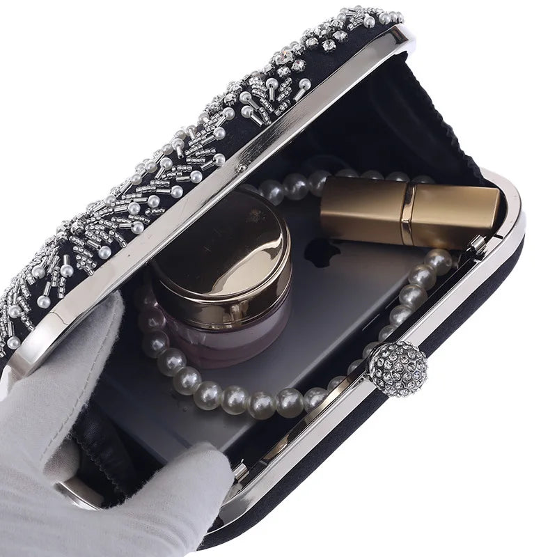 pearl embellished evening clutch bag open showing pearl necklace, lipstick, and cosmetic jar inside