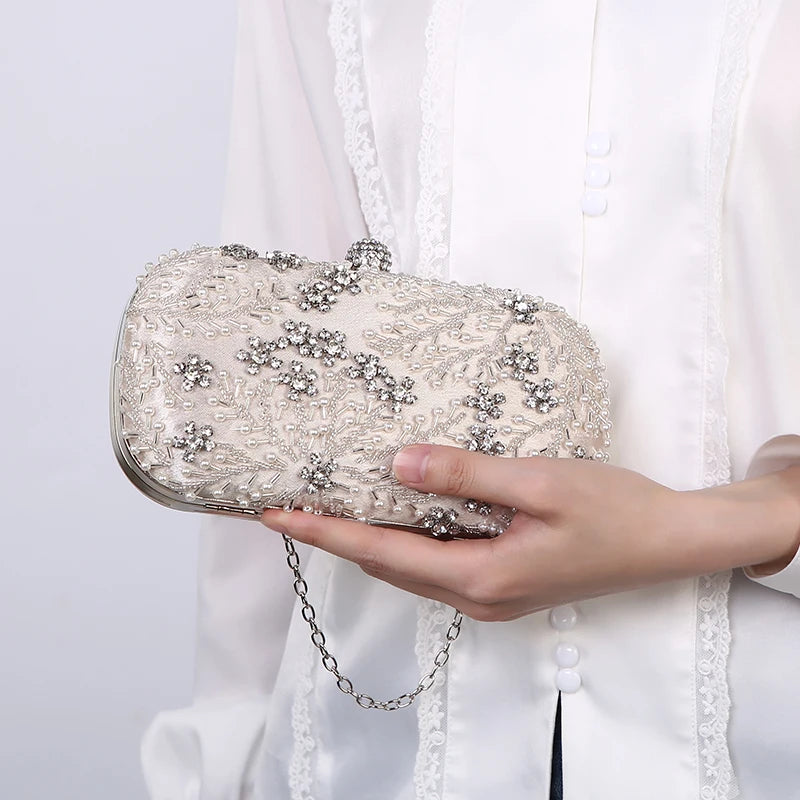 Pearl embellished evening clutch bag with silver bead details held by person in white lace blouse