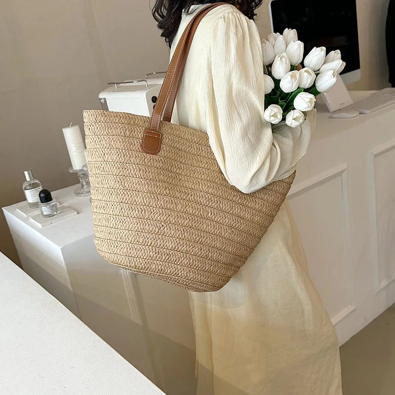 Woman carrying a luxury woven shopper tote with leather handles and holding white tulips