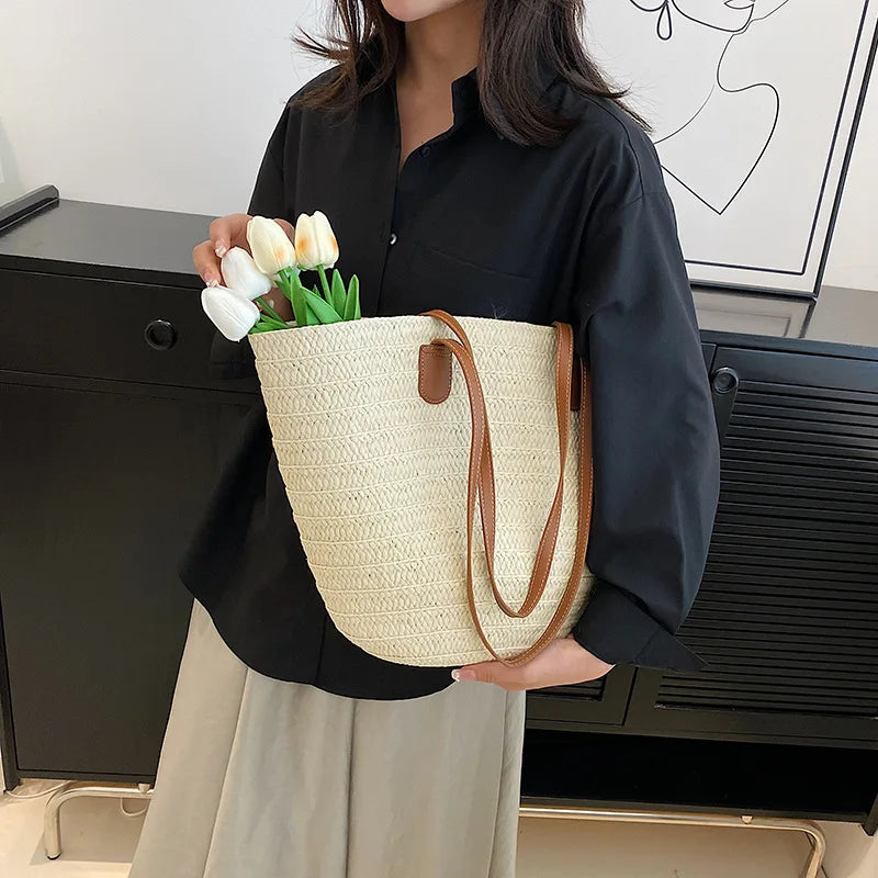 Stylish woman holding a luxury woven shopper tote with leather straps and tulips inside