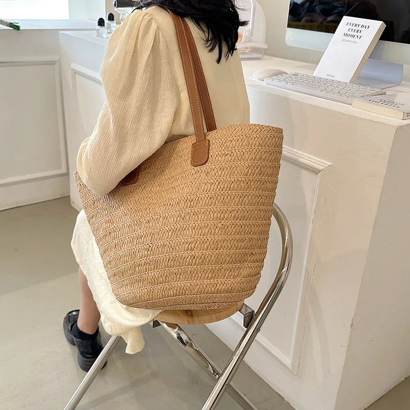 Stylish woman wearing a white dress with a luxury woven shopper tote featuring brown leather handles