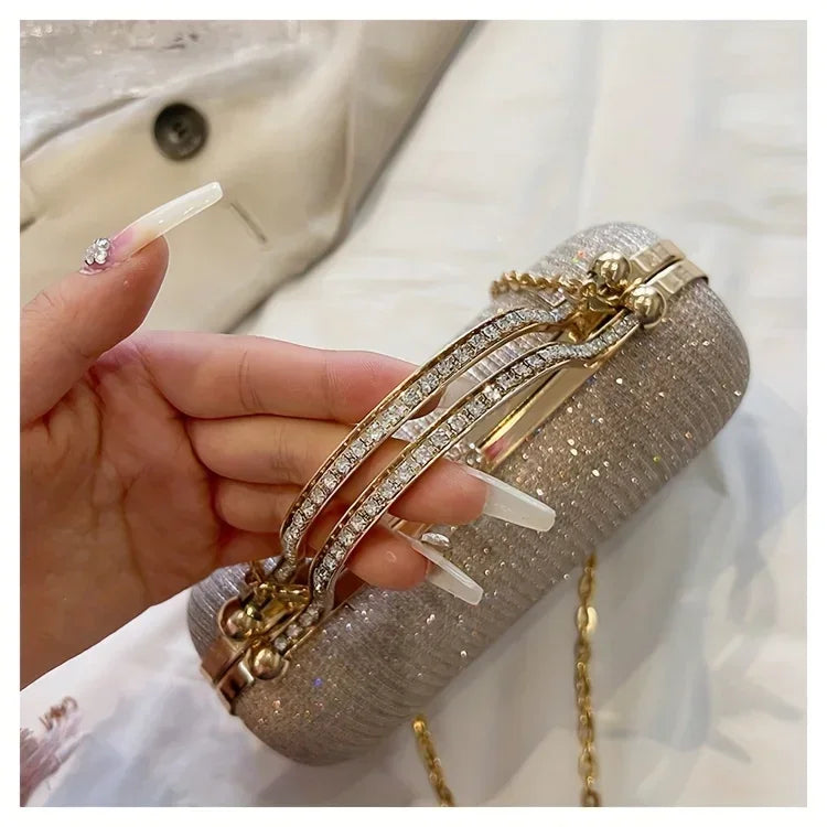 Elegant rhinestone evening bag with a gold frame and chain strap held with manicured hand