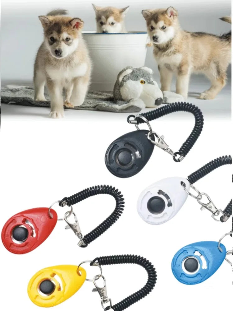 Various dog training clickers in red, black, white, and yellow with wrist straps and playful puppies in background