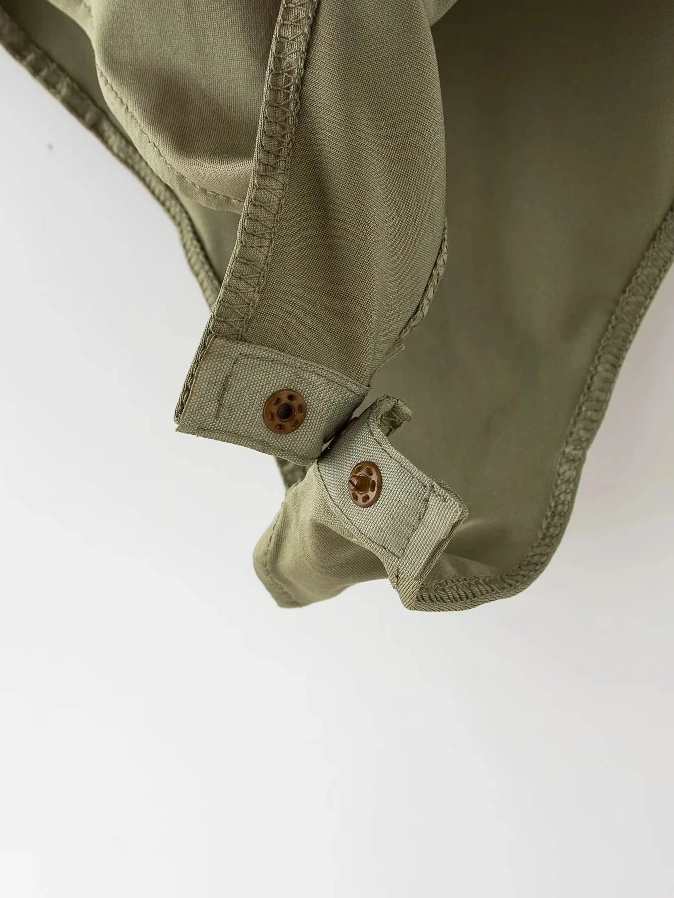 Close-up of green summer slim bodysuit showcasing secure snap buttons and soft fabric details