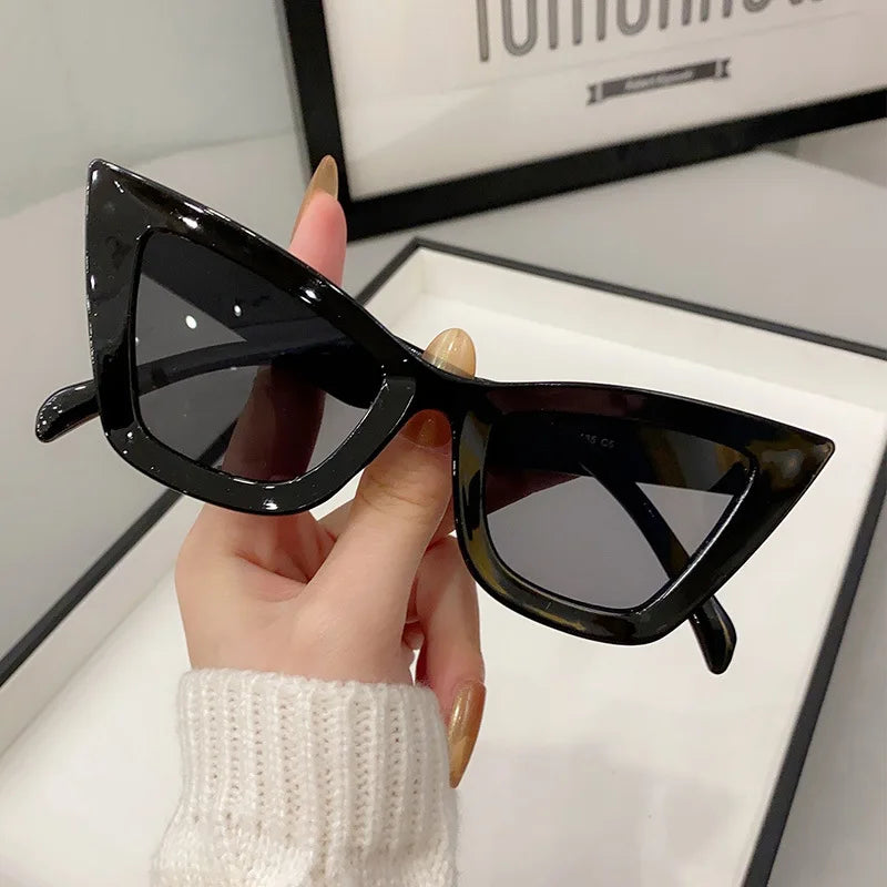 VaultHaus black vintage cat eye sunglasses for women with glossy frames held by a hand.