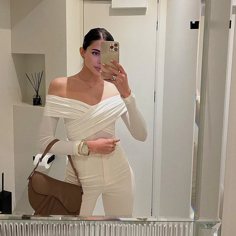 Stylish woman wearing a sexy off shoulder bodysuit with long sleeves and chic white pants