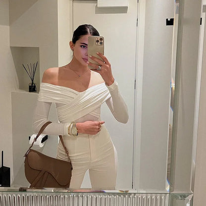 Stylish woman wearing a sexy off shoulder bodysuit with long sleeves and chic white pants