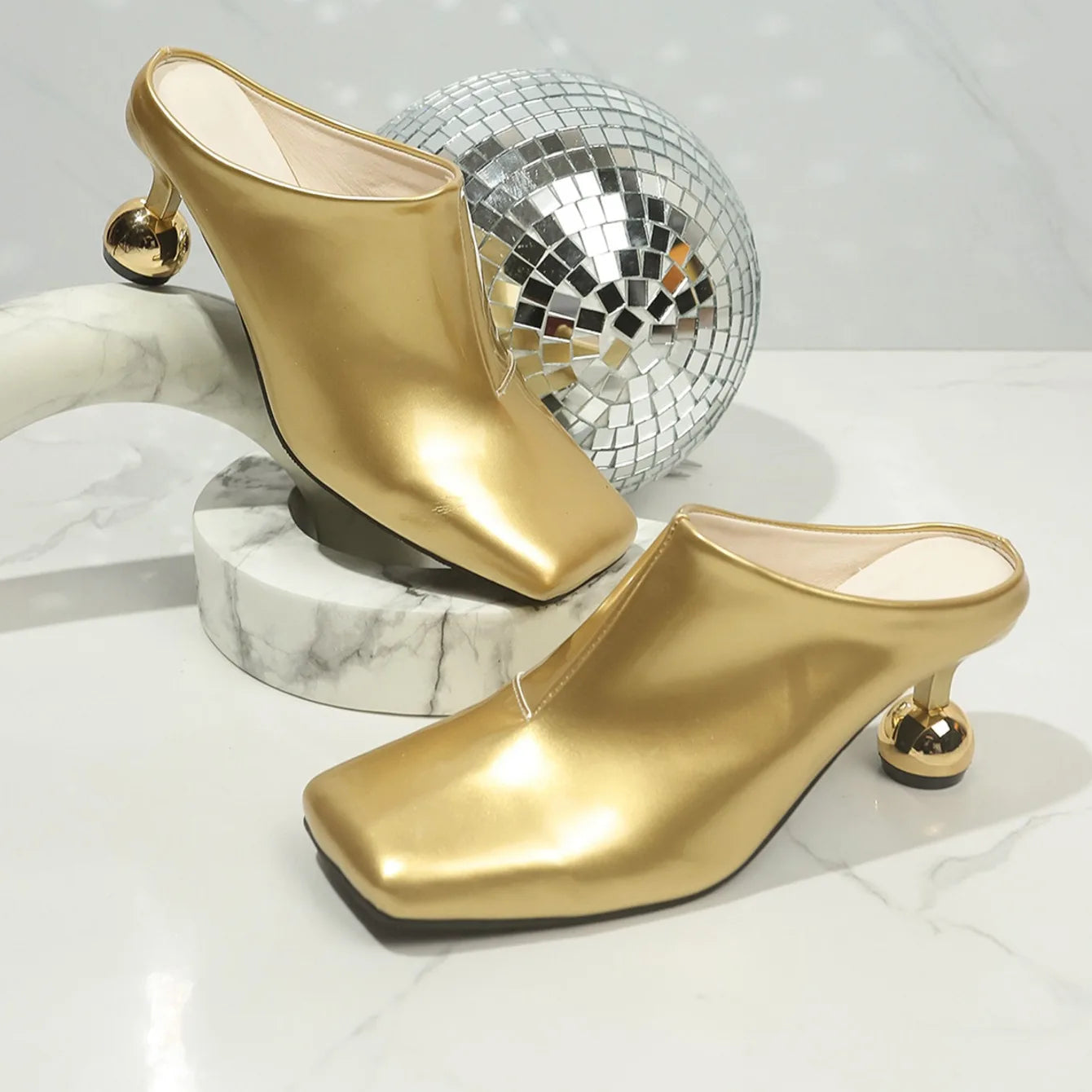 VaultHaus designer women's wedge sandals in gold with unique spherical heels on marble surface