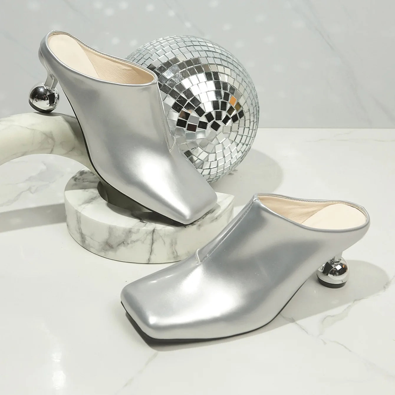 VaultHaus designer women's wedge sandals in silver with unique round heels on marble surface