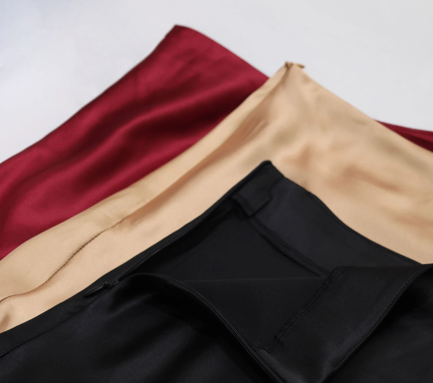 VaultHaus Women's satin elegant midi skirt in black, beige, and burgundy colors showcasing luxurious fabric texture