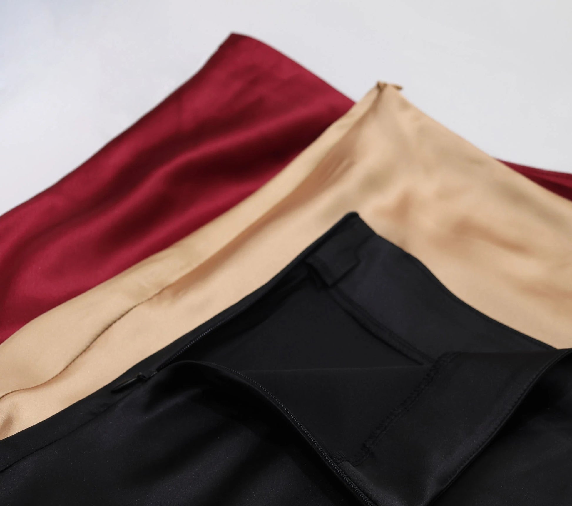VaultHaus Women's satin elegant midi skirt in black, beige, and burgundy colors showcasing luxurious fabric texture