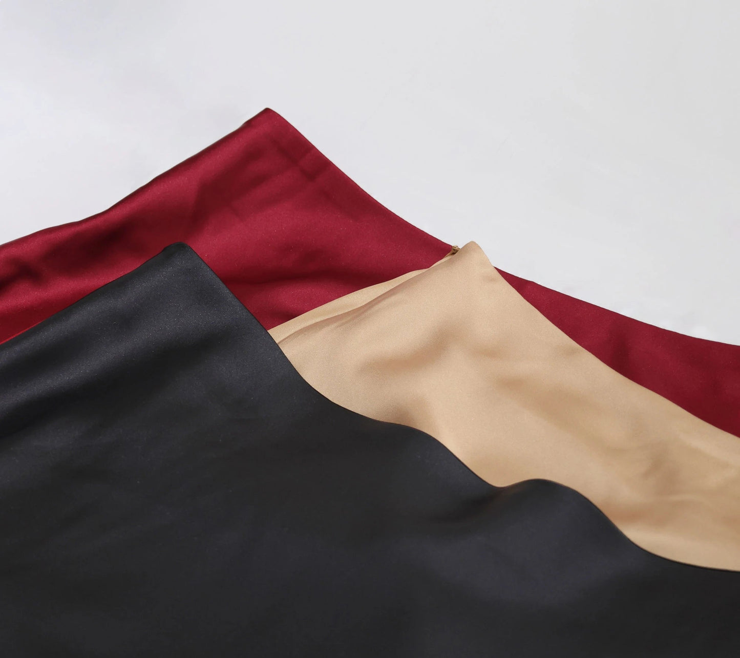 Women's satin elegant midi skirt in black, burgundy, and beige fabric, perfect for formal occasions.