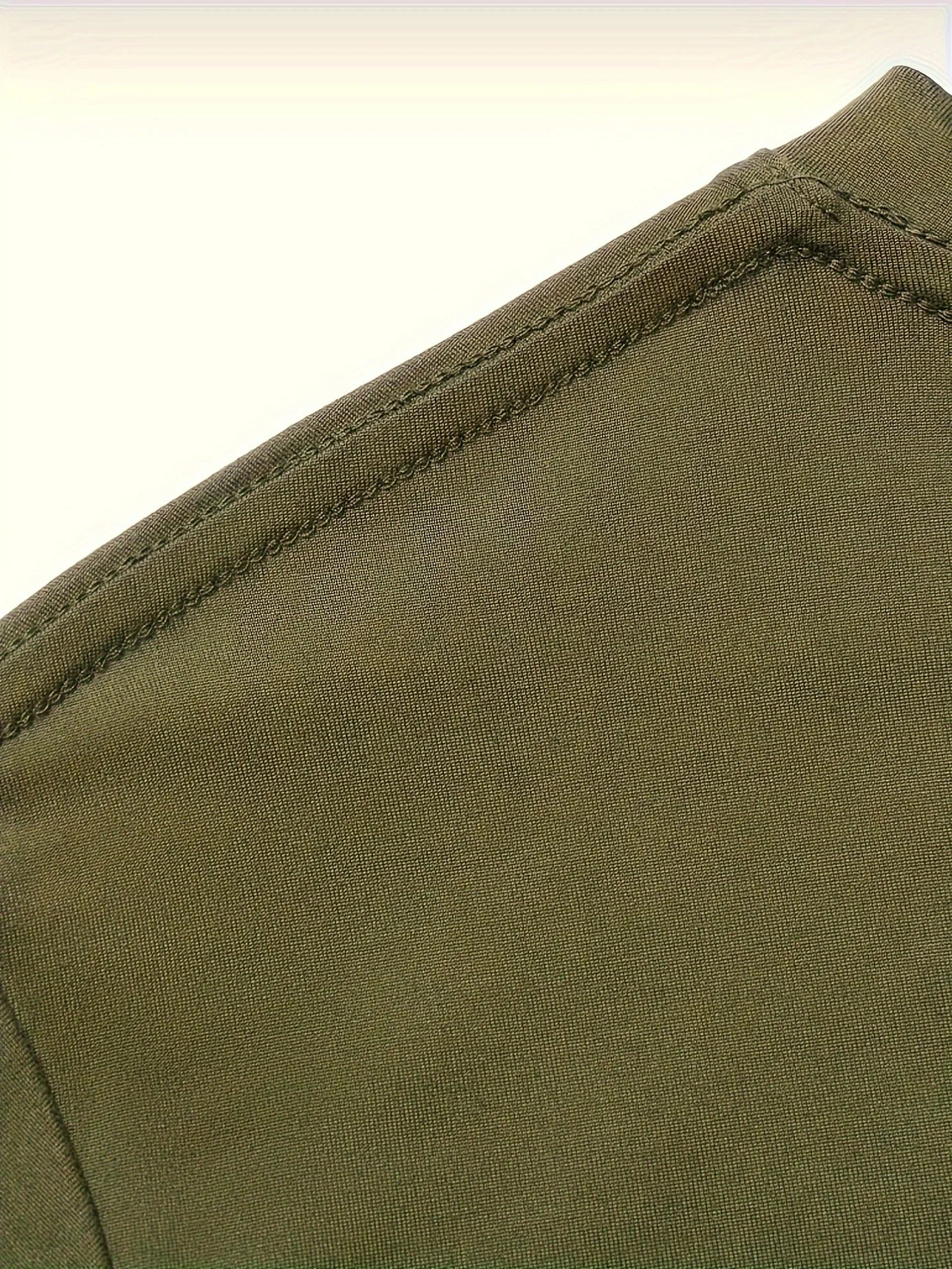 Close-up of the shoulder seam on a men's cotton compass t-shirt from VaultHaus in olive green