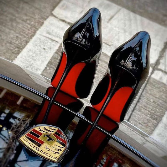 Elegant sexy red bottom heels positioned on a sleek black surface, showcasing their stylish design