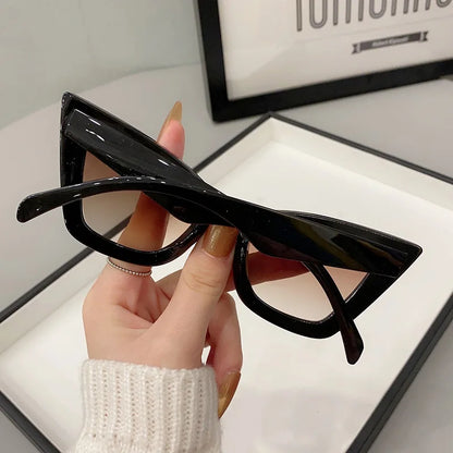 VaultHaus black vintage cat eye sunglasses for women held in hand with beige sweater background